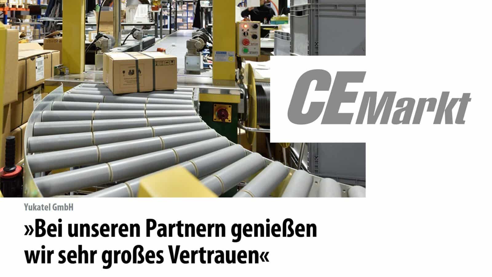 Kartons auf Förderband in einer Lagerhalle, CE Markt Logo, Text: Bei unseren Partnern genießen wir sehr großes Vertrauen.