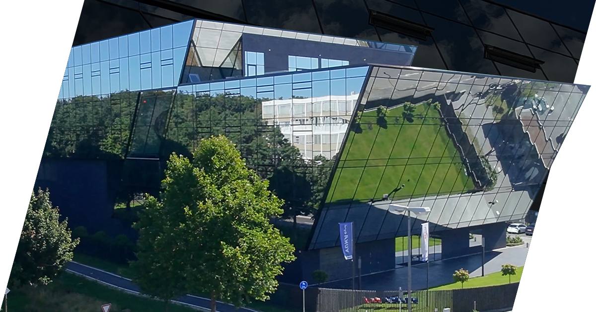 Modernes Gebäude mit verspiegelter Fassade und reflektiertem grünen Park in der Umgebung.